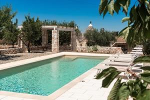 una piscina con sedie a sdraio accanto a una casa di Trullo Felicità a Putignano