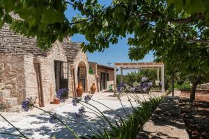 un giardino con un edificio in pietra e un pergolato di Trullo Felicità a Putignano
