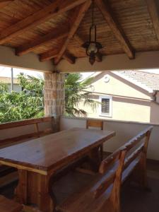 a wooden table and two benches on a patio at Apartman Iris in Gabonjin
