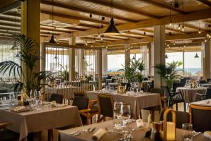 a restaurant with white tables and chairs and windows at Marea Suites, Valamar Collection in Poreč +35 photos