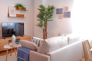 a living room with a white couch and a palm tree at R2R - Casa RTPG Castrillón - 11A02 in Salinas