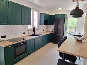a kitchen with green cabinets and a table with chairs at Sun Anna Apartments in Pag
