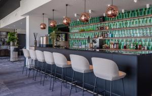 a bar with white chairs and green shelves at Kyriad Chateauroux Nord - Aéroport in Déols