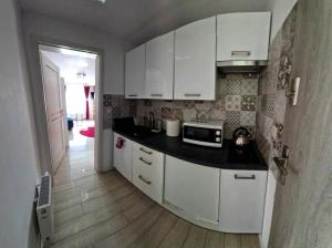 kuchnia z białymi szafkami i czarnym blatem w obiekcie Apartamenty Orchidea Łeba w Łebie