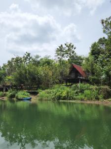 a house on the side of a river with a boat at Wulenpari EcoVillage in Sambipilu