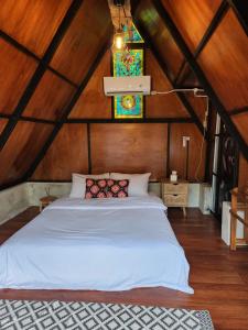 a bedroom with a white bed in a attic at Wulenpari EcoVillage in Sambipilu