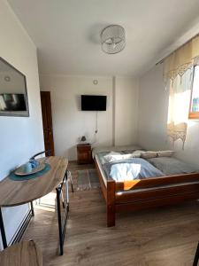 ein Schlafzimmer mit einem Bett, einem Tisch und einem Fernseher in der Unterkunft Pokoje Gościnne Bartuś in Czarna Góra