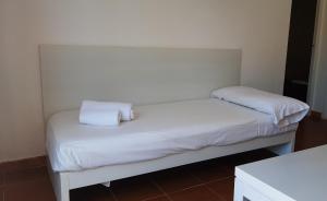 a white bed with two pillows on top of it at Aparthotel FLORA PARK & AQUAROCK in Cala en Bosc