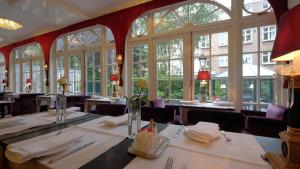 uma sala de jantar com mesas, cadeiras e janelas em Apollofirst Boutique Hotel em Amsterdã