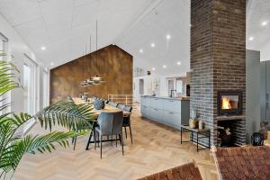 a kitchen and dining room with a table and a fireplace at Exclusive Pool And Activity House For 30 People -1002 in Ringkøbing