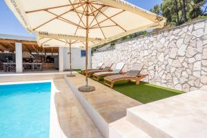a patio with chairs and an umbrella next to a pool at Villa Lucija in Milna