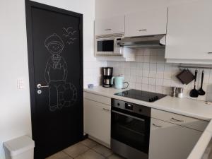 una cucina con una porta nera con un disegno sopra di Le char à voile a De Panne