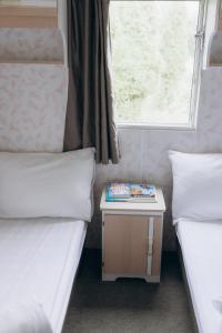 a room with two beds and a table with a book at Atvases in Pērkone