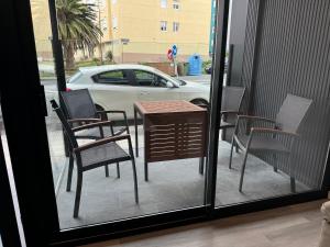 een tafel en stoelen op een patio met uitzicht op een auto bij Apartamentos Turísticos Vidal Costa in Foz
