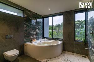 ナーシクにあるStayVista at The Rainfield Villa with Gazebo & Lawnのバスルーム(バスタブ、トイレ、窓付) +24枚の写真
