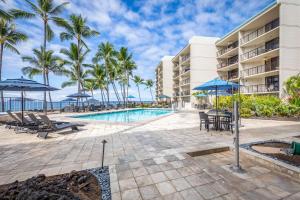 a resort pool with tables chairs and umbrellas at Aston Kona By The Sea in Kailua-Kona