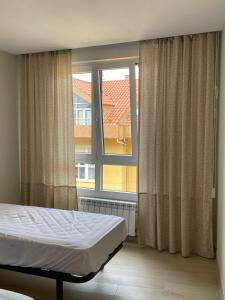 ein Schlafzimmer mit einem Bett und einem großen Fenster in der Unterkunft Apartamento Recién Reformado en Somo junto iglesia in Somo