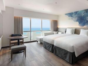 a hotel room with two beds and a view of the ocean at Grand Mercure Okinawa Cape Zanpa Resort in Yomitan