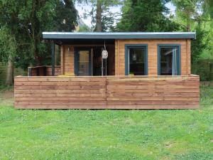 a small cabin with a wooden deck in the grass at Guldborg Camping & Cottages - Superior in Guldborg