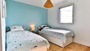 two beds in a room with a window at Villa des Loups de Mer in Talmont