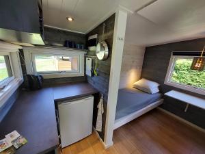 a small room with a bed and two windows at Guldborg Camping & Cottages - All you need in Guldborg