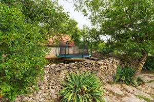 a playground in a stone wall with a blue trampoline at Ferienhaus Jadranka in Kistanje