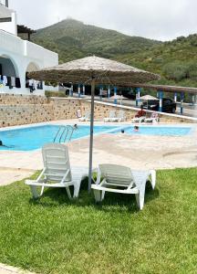 two lounge chairs and an umbrella next to a pool at Appartement familial avec balcon et piscine in Martil