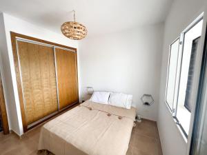 a bed in a room with a window and a chandelier at Appartement familial avec balcon et piscine in Martil