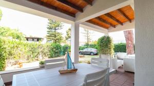 a porch with a white table and chairs and a view of a car at Villa Brezza di Mare-Geremeas Country Club in Maracalagonis