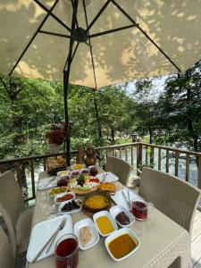 a table with plates of food on it with an umbrella at IVA House in Çamlıhemşin