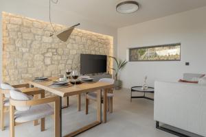 a living room with a dining room table and a stone wall at Piccadill Luxury Villas in Methoni