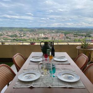 a table with plates and wine glasses on a balcony at Nid d'Aigle - Parking et vue exceptionnelle sur Carcassonne in Carcassonne
