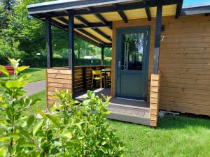a cabin with a blue door and a deck at Guldborg Camping & Cottages - All you need in Guldborg
