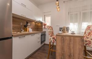 una cucina con armadi bianchi e bancone con sedie di Nice Apartment In Biograd Na Moru a Biograd na Moru