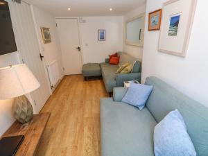 a living room with a blue couch and a table at Cormorant Cottage in St Ives