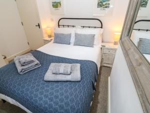 a bedroom with a bed with towels on it at Cormorant Cottage in St Ives