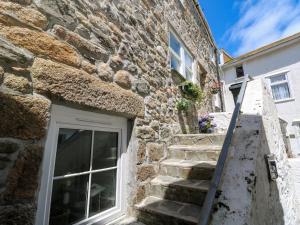 a stone house with stairs and a window at Cormorant Cottage in St Ives