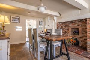 a dining room with a table and a brick fireplace at Skeet Cottage in Burnham Market