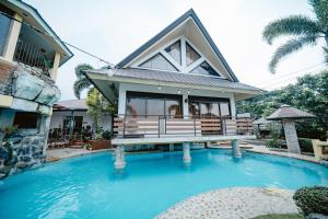 a house with a swimming pool in front of a house at Pina Colina Resort Tagaytay City by RedDoorz in Tagaytay