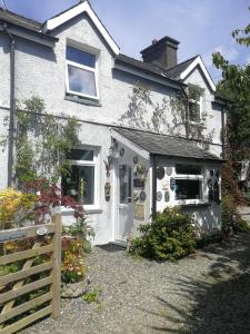 a white house with a white door and a fence at Yr Hen Farcdy in Talsarnau