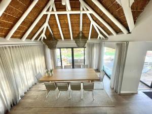 a dining room with a wooden table and chairs at Laid back luxury canal house in St Francis Bay