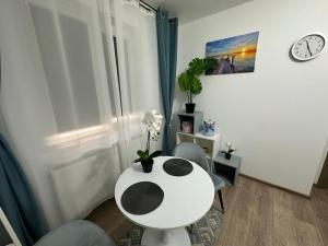 a room with a white table and chairs and a clock at Mira Studio in Popeşti-Leordeni