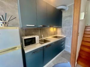 a kitchen with blue cabinets and a sink and a microwave at Appartamento Zipser II in Grado