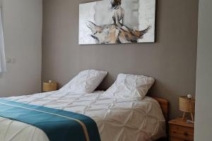 a bed in a bedroom with a painting on the wall at Villa tout confort avec piscine in Mauguio