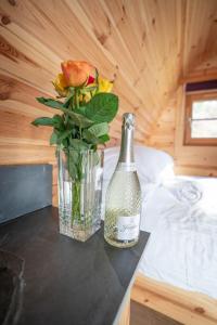 a bottle and a vase with flowers on a table at Ocean View with hot tub in Barmouth +13 photos