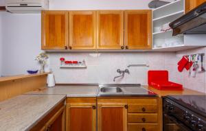 a kitchen with wooden cabinets and a sink and a red chair at 2 Bedroom Amazing Apartment In Pinezici in Pinezici