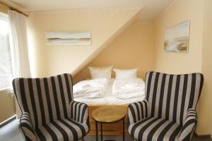 a bedroom with two chairs and a bed in the attic at Apartmentanlage Eldena Ferienwohnung 10 in Lobbe