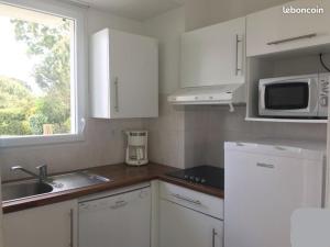 Una cocina con gabinetes blancos y un fregadero y una ventana. en Maison 4-6 personnes, en Saint-Brevin-les-Pins