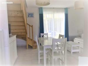 Un comedor con mesa y sillas y una escalera. en Maison 4-6 personnes, en Saint-Brevin-les-Pins 4 fotos más