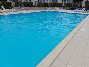 una piscina con sillas y agua azul en Maison 4-6 personnes, en Saint-Brevin-les-Pins
